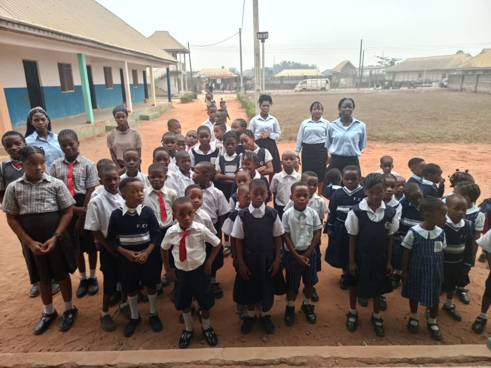 The whole school lined up on the sand outside the classroom block, with staff standing at either end of the rows.
